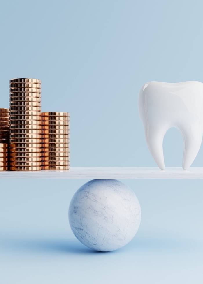 A fake tooth balanced against a pile of coins on a marble ball and plank