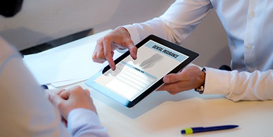 A person showing someone a digital pad with ‘dental insurance’ listed