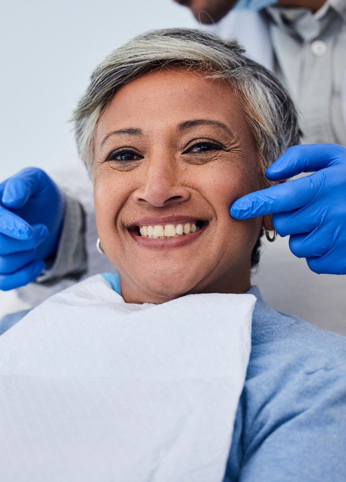 Patient smiling while holding small mirror with dentist