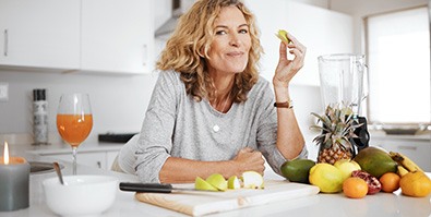 Woman smiling while eating fruit in kitchen