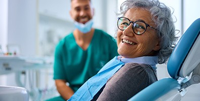 Woman with black glasses smiling at dental checkup