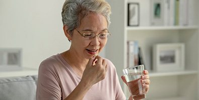 a woman taking a pill with a glass of water